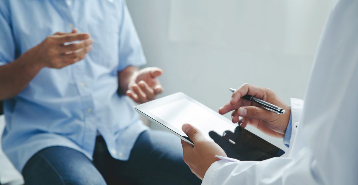 Doctor-consulting-with-a-patient-while-holding-a-tablet-device