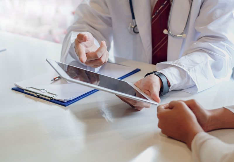Doctor-discussing-treatment-options-with-patient-on-tablet Doctor-discussing-treatment-options-with-patient-on-tablet