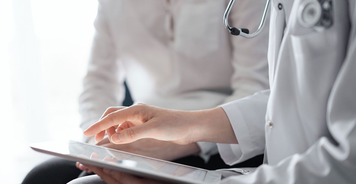 Doctor-reviewing-medical-information-on-tablet-with-patient Doctor-reviewing-medical-information-on-tablet-with-patient