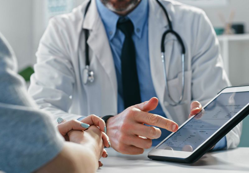 Doctor-reviewing-medical-results-with-patient-on-tablet Doctor-reviewing-medical-results-with-patient-on-tablet
