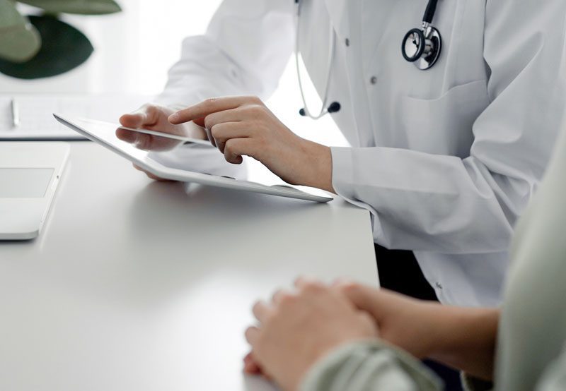Doctor-reviewing-patient-information-on-tablet Doctor-reviewing-patient-information-on-tablet