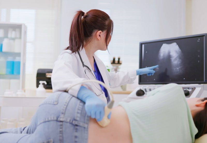 Doctor-reviewing-ultrasound-image-with-patient-during-exam Doctor-reviewing-ultrasound-image-with-patient-during-exam